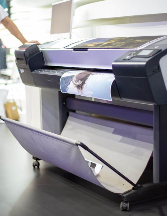 plotter prints a poster. standing next to people in blur. close-up, background in blur plotter prints a poster. standing next to people in blur. close-up, background in blur